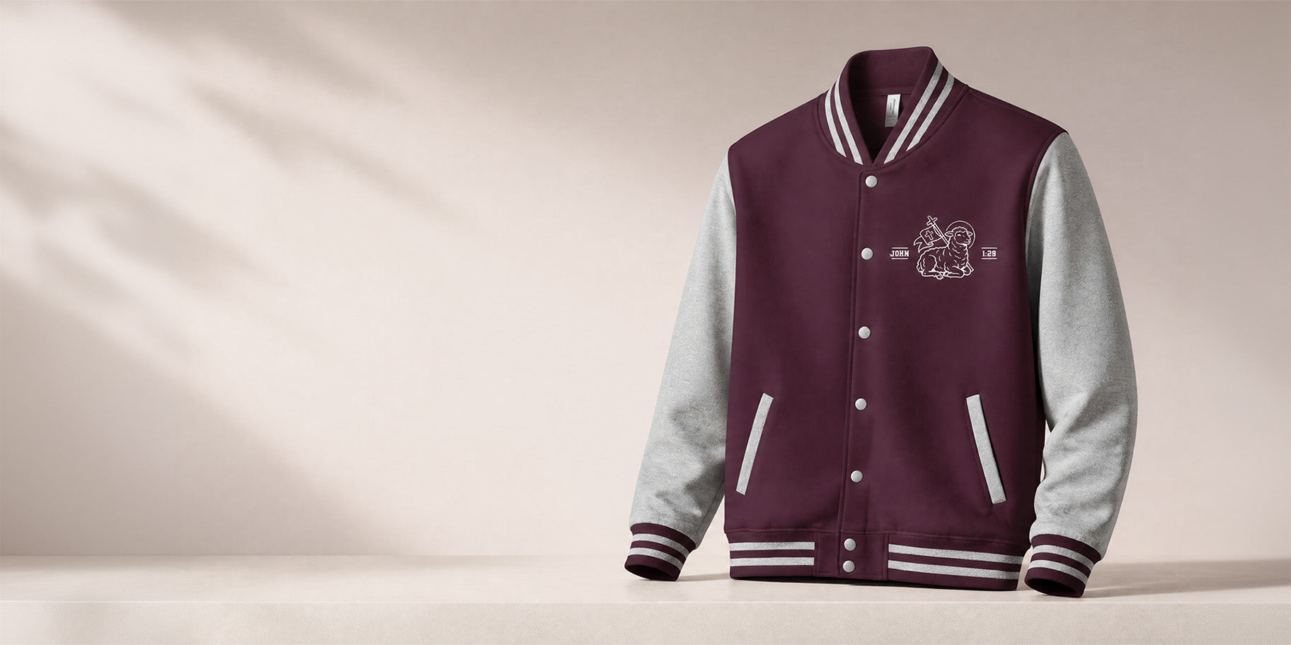 Maroon and grey varsity letterman jacket embroidered with a lamb and cross graphic and a "John 1:29" scripture reference.