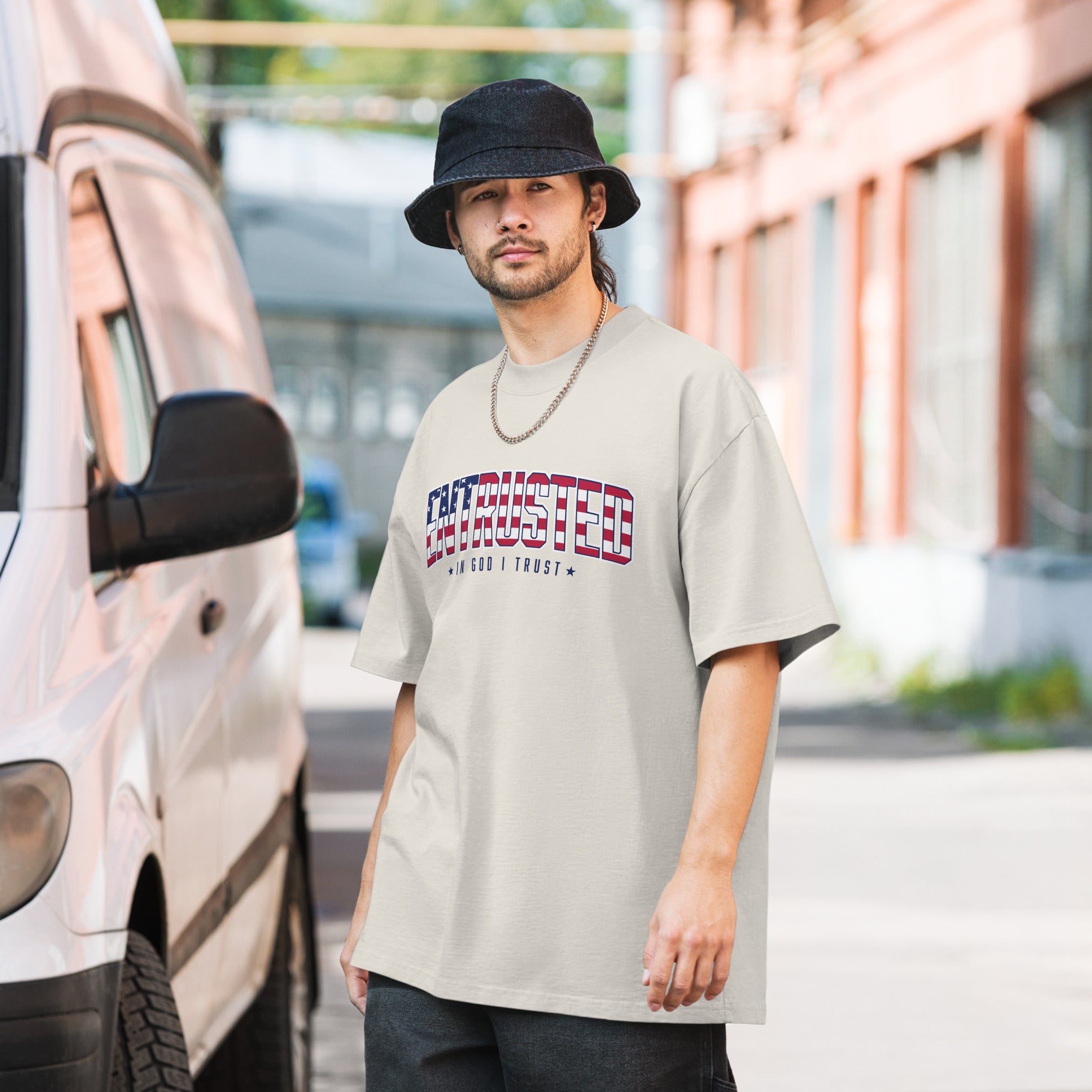 Image of Man wearing the Faded Bone Entrusted patriotic oversized tee with American flag design on a city street