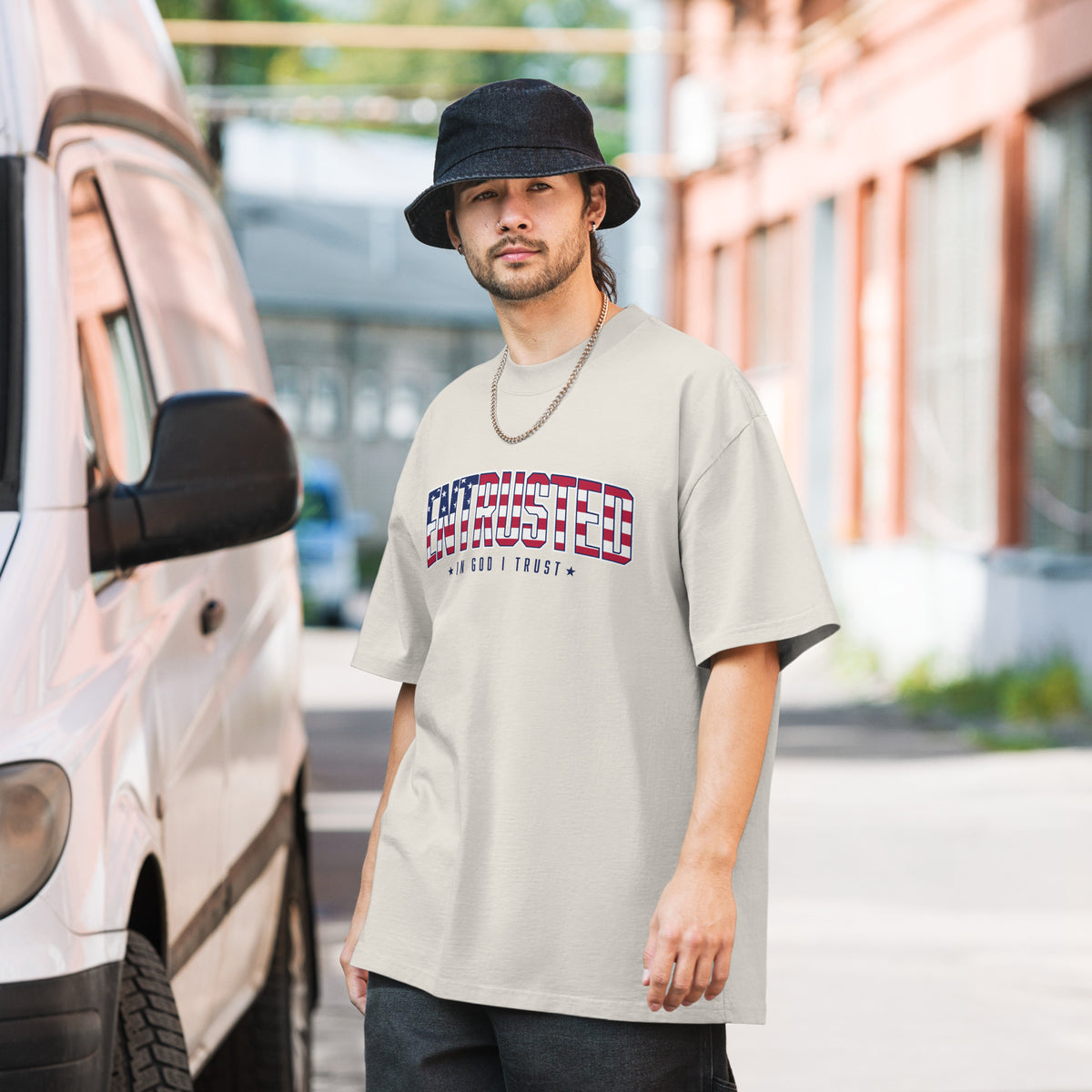 Man wearing the Faded Bone Entrusted patriotic oversized tee with American flag design on a city street