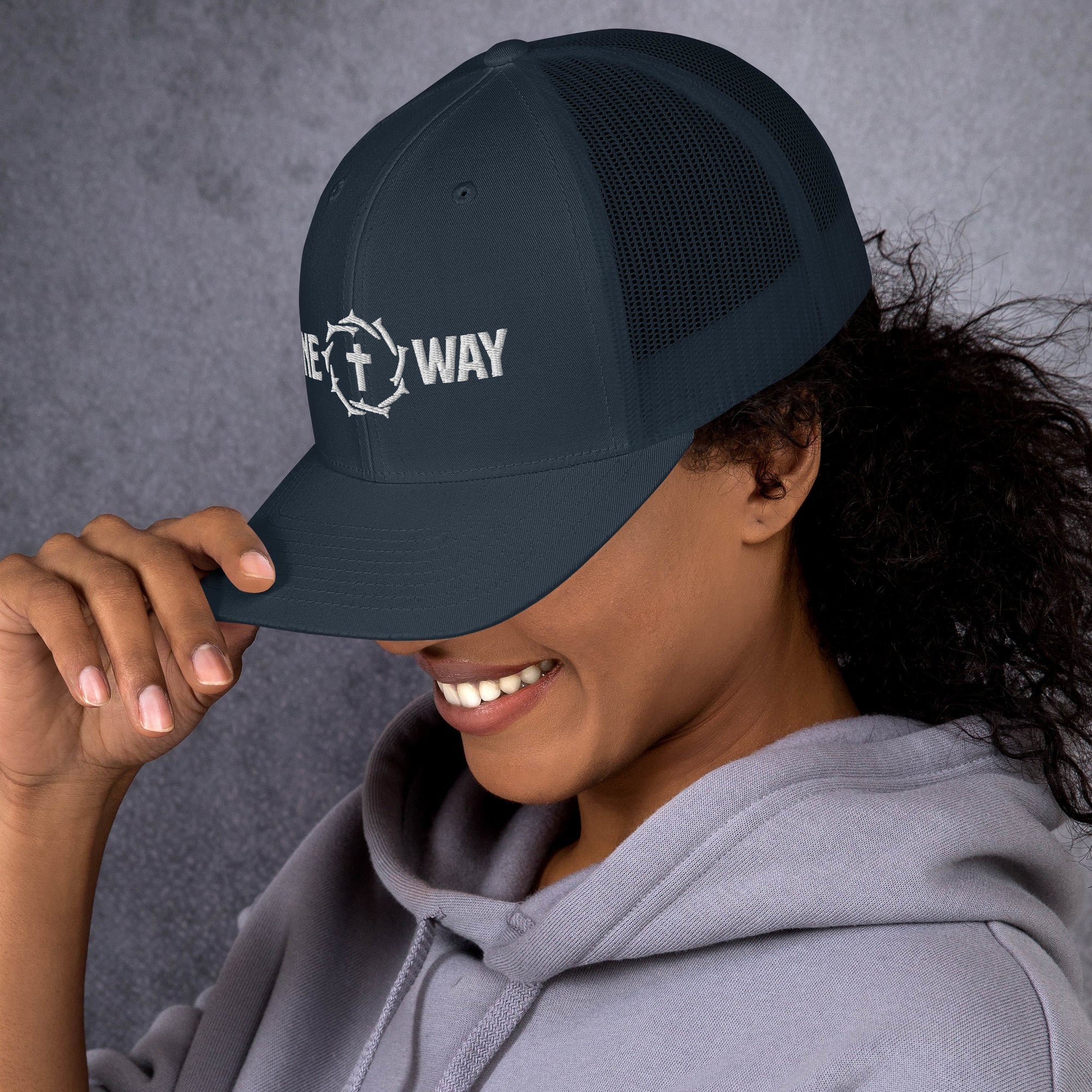 Image of Woman wearing the One Way embroidered trucker cap in navy, smiling under the brim