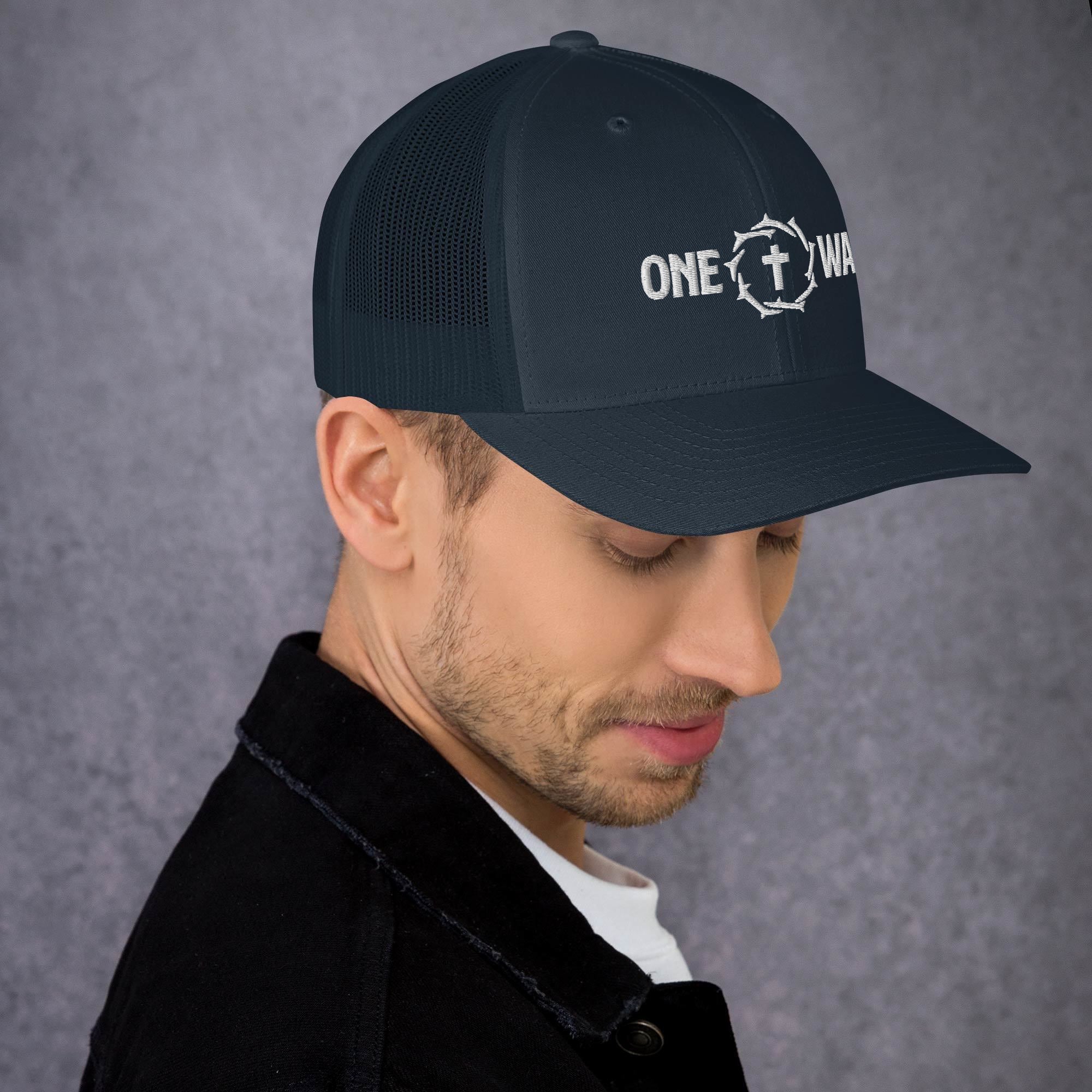 Image of Man wearing the One Way embroidered trucker cap in navy, looking down