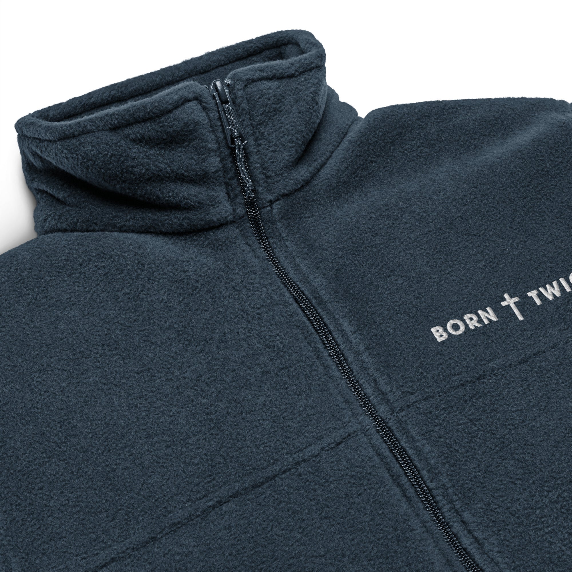 Image of Close-up of the embroidered BORN TWICE cross wordmark, zipper and fleece collar on the collegiate navy Columbia jacket